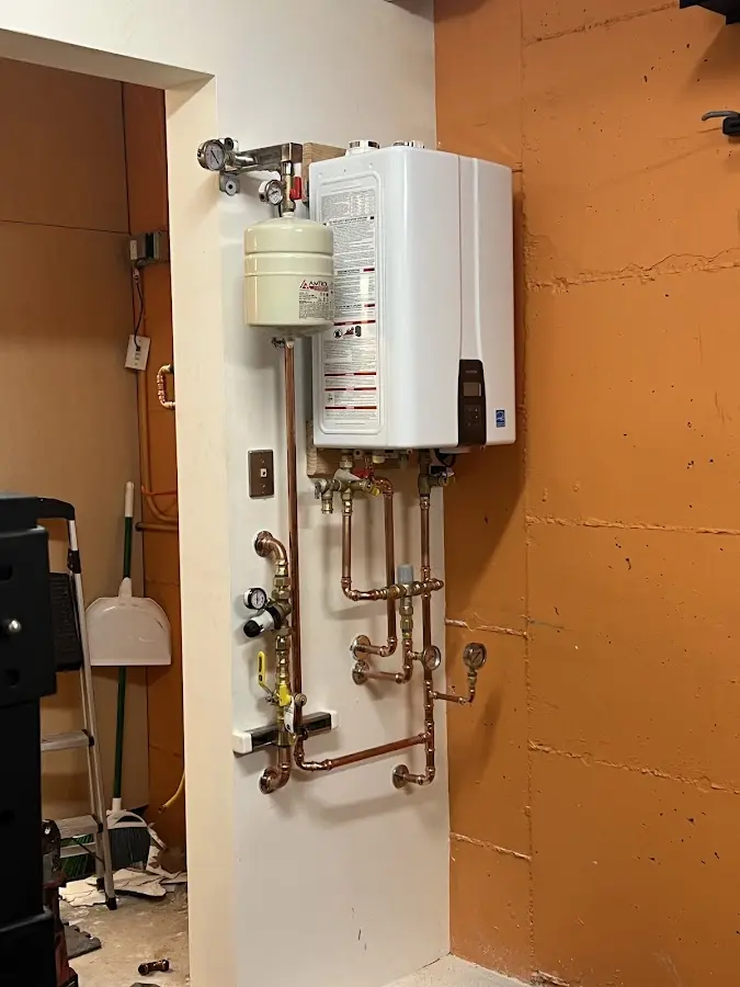 Plumbing technician inspecting water heater connections in West Brookfield